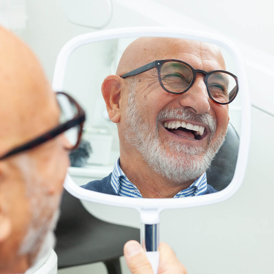 senior male patient looking at the mirror after dental treatment