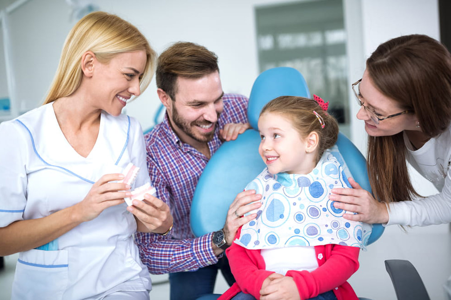 Young female dentist tells a little girl what a tooth with a tooth looks