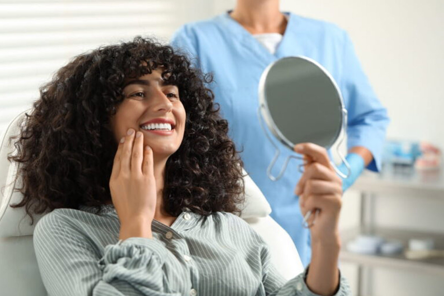 Patient looking in mirror and doctor in clinic, selective focus. Dental veneers